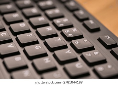 Side Angled Top View Macro Close-Up Black Computer Keyboard Highlighting T Key with Soft Blurred Tech Backgrounds