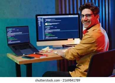 Side back view smiling young full-stack developer software engineer IT specialist programmer man in shirt work at home writing code on laptop pc computer checking database. Program development concept