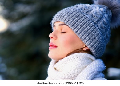 Side beauty portrait of beautiful attractive girl, young calm woman is breathing deep deeply fresh air at winter cold frosty snowy day with her eyes closed, meditating, doing breath exercise, enjoying
