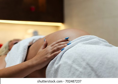 Side and below view of happy and smiling beautiful futuristic mom. Pregnant woman lying on bed covered with white cotton towels. She feeling her baby in stomach. - Powered by Shutterstock