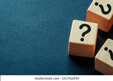 Side border of question marks on wooden cubes over a dark blue textured background with copy space