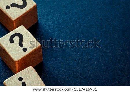 Side border of question marks on wooden cubes over a dark blue textured background with copy space