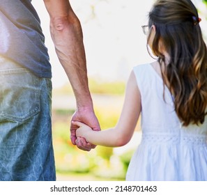 Side by side, hand in hand. Rear view shot of a little girl holding her fathers hand outside. - Shutterstock ID 2148701463