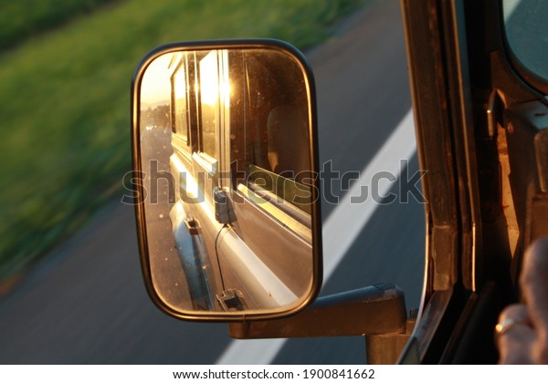 Side car mirror\
reflecting sunset light 