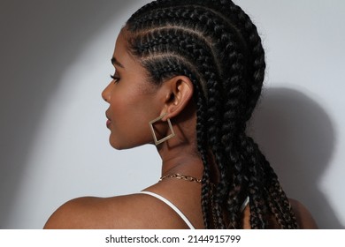 Side close-up of African young woman with braids posing on white background.