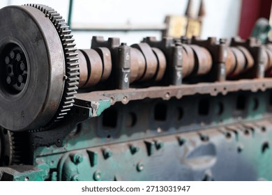 A side close-up view of an exposed engine block and camshaft with a large gear, showing industrial scale and rusty mechanical components.