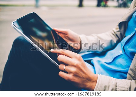 Side cropped view of female hands tapping on touch pad screen for searching information during leisure in city, millennial woman have chatting during pda communication via modern digital tablet