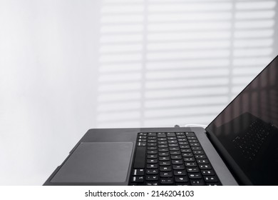 Side cropped view of the laptop computer in light modern workspace. Workplace or home office of programmer or freelancer. Online remote working, distant learning, work from anywhere concept. Close up