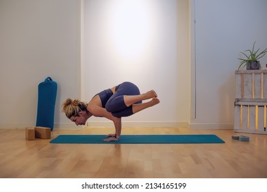 side crow pose yoga position - woman performing Parsva Bakasana pose indoors - Powered by Shutterstock