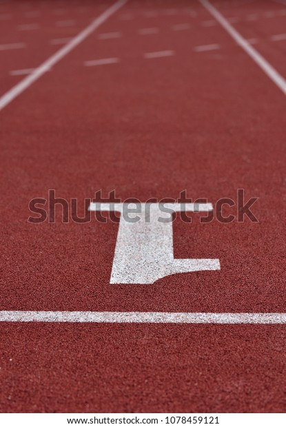 An up side down white number 1 on a\
starting line of a running track field with two straight white\
lines running paralleled toward the finished\
line.