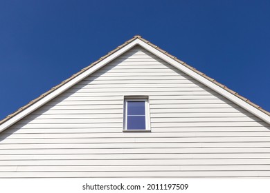 Side Elevation And Roof Of A New Build House With White Cladding Against A Blue Sky. Hertfordshire, UK