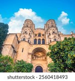 Side entrance of the Malaga Cathedral (la manquita) behind a lovely garden with ornamental butter orange trees, Malaga, Andalusia (Andalucía), Spain