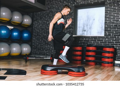 Side Full Body View Of Sporty Athlete Man Doing Step Up Jumps In Health Fitness Club. The Handsome Male Is Exercising His Legs On The Stepper In The Modern Gym. Sport, Lifestyle And People Concept.