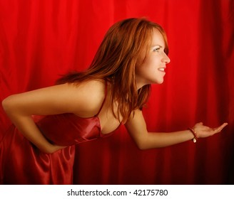 Side Half Body Portrait Of Young Woman Taking Bow On Stage With Red Curtains In Background.