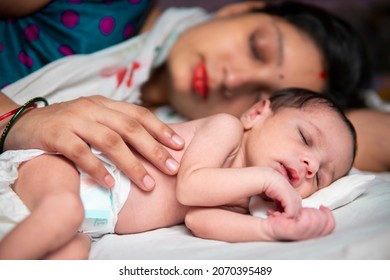 Side Image Of Image Of Beautiful Indian Mother And Her Cute Newborn Baby Sleeping Peacefully In Bed At Home. 