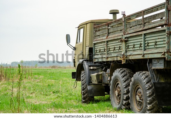 Side of a\
Military Truck with its bed on green\
field
