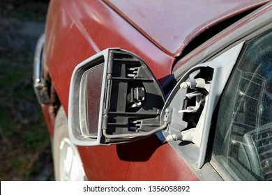 The Side Mirror Of The Car Is Almost Detached From The Body Of The Car.