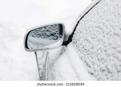 the side mirror of the car , completely covered with fluffy snow after a snowfall