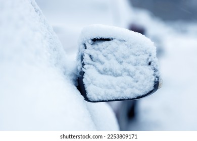 The side mirror of a car covered in snow. Selective focus