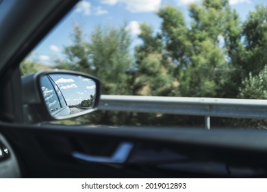 A side mirror of the car with a reflection seen from insi