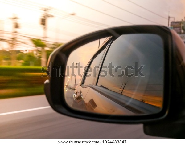 Side mirror of\
Car, Running on the street, The light and atmosphere of the sun\
rising, transportation\
background.