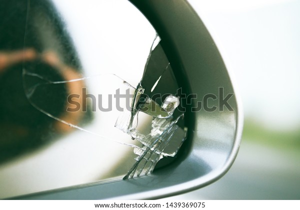 Side mirror of the car with a view back. Broken\
mirror close up.
