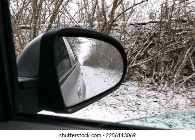 Side mirror of a car.Traveling by car in winter.View from the car.Snowy weather.Bad weather conditions.Off-road.Problems on the road.Automotive .