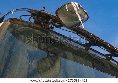 Side mirror with icicles on tractor cab during cold winter weather outdoors
