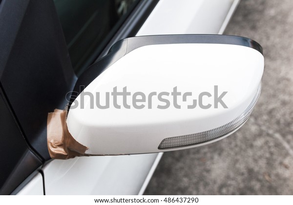 Side\
mirror of white car broken. Fix with adhesive\
tape.