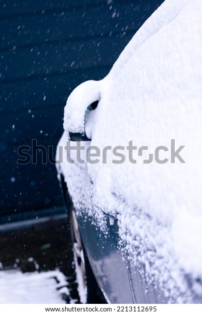 A side mirror and side window of a car at the\
driver side covered in white snow during winter season. In order to\
start driving the driver will have to clear the snow or wait for it\
to melt.