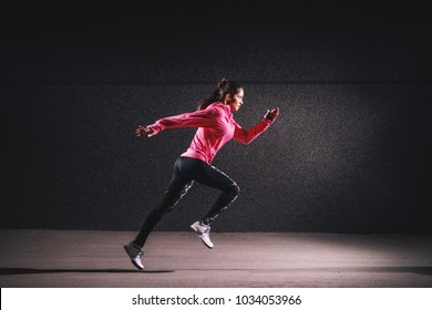 Side motion view of attractive sporty athlete running girl in sportswear at the street in front of the grey wall.  - Powered by Shutterstock