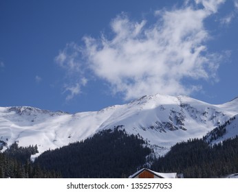 A side of a mountain with some clouds in the background