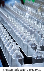 Side Perspective Close Up On Tiered Rows Of Clear Glass Bottles For A Ring Toss Game At A Carnival Boardwalk