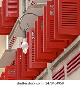 A side perspective view of open, red wooden venetian shutters. 