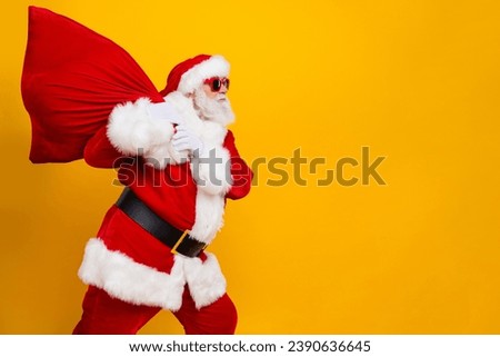 Side photo of overweight saint nicholas wear red costume walking bring huge bag with gifts for kids isolated on yellow color background