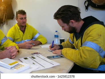 Side pictures of construction workers sitting on the chair table brainstorm writing job hazard analysis risk assessment control working at height and confined space permit prior starting each task    