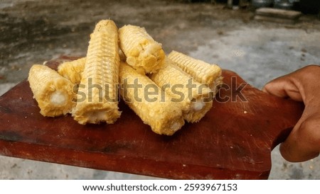 from the side, a pile of corn cobs on a wooden cutting board