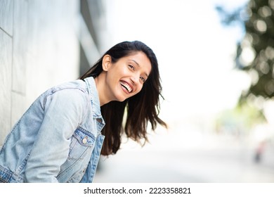 Side portrait attractive young woman leaning against wall and laughing  - Shutterstock ID 2223358821