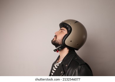 Side Portrait Of Biker Man Posing In Leather Jacket And Blue Motorcycle Helmet.