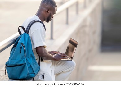 Side portrait of black man using laptop in the street