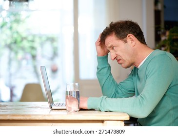 Side Portrait Of A Confused Man Using Laptop At Home