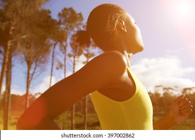 Side portrait of fit african woman running outdoors on a sunny day - Powered by Shutterstock