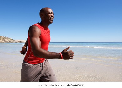 Side portrait of fit and happy young black man walking along the seashore
