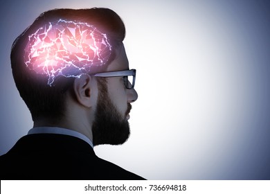 Side portrait of handsome caucasian busiessman in glasses with glowing digital brain on gray background. Artificial mind concept 