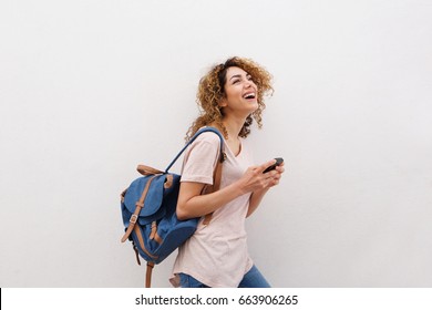 Side Portrait Of Happy Young Woman Walking With Bag And Cellphone