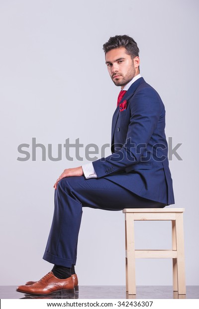 スタジオでカメラを見ながら座るビジネススーツを着た男性の横のポートレート の写真素材 今すぐ編集