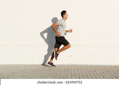 Side portrait of middle age man running by white wall
