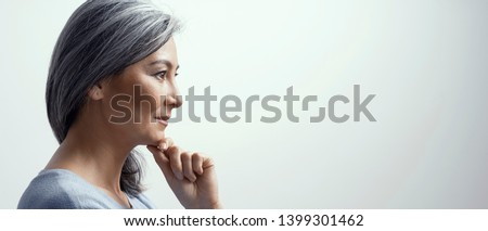 Side Portrait Of Smiling Asian Woman With Grey Hair Touching The Chin. Beautiful Middle-Aged Woman In Profile Touching Chin