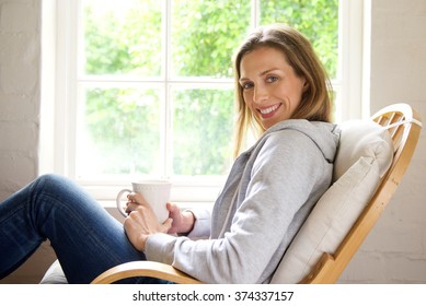 Side Portrait Of A Smiling Older Woman Relaxing At Home With Cup Of Tea