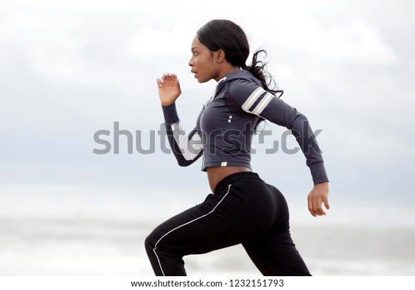 走る活発な若い黒人女性の横のポートレート の写真素材 今すぐ編集
